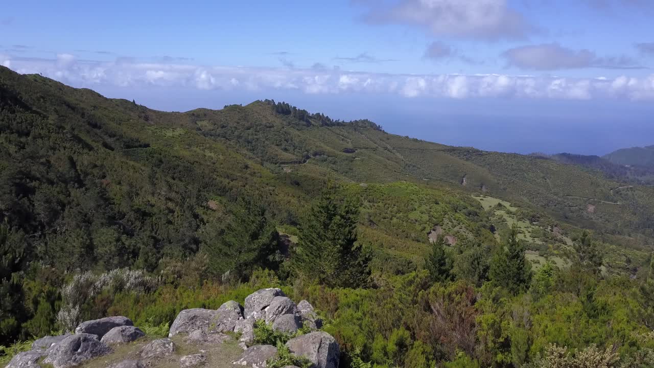 madeira, portugal - hombre caminando hasta la cima de la montaña rocosa con vistas a la exuberante cordillera en un día soleado - toma aérea de drones