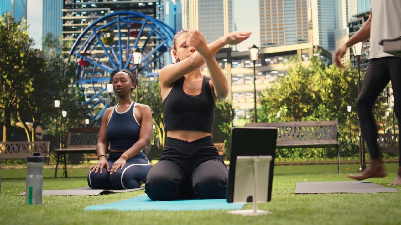 Young woman practices torso stretching exercise seated in front of tablet