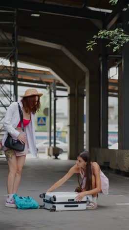 two women unpacking luggage at a train station