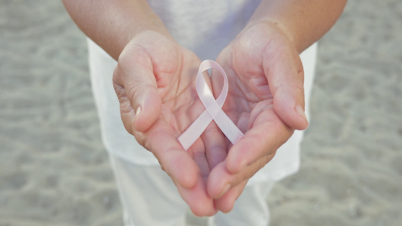 Nastro di consapevolezza del cancro al seno nelle mani della donna