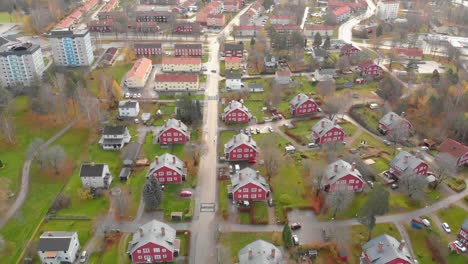 drone footage flying over some beautiful red houses surrounded with green grass in a small town in sweden