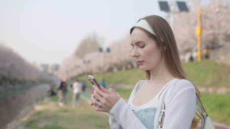 Hübsche-Junge-Dame,-Die-Im-Yangjae-Citizen&#39;s-Forest-Park,-Bezirk-Seocho,-Stadt-Seoul,-Südkorea,-Auf-Ihrem-Smartphone-Chattet