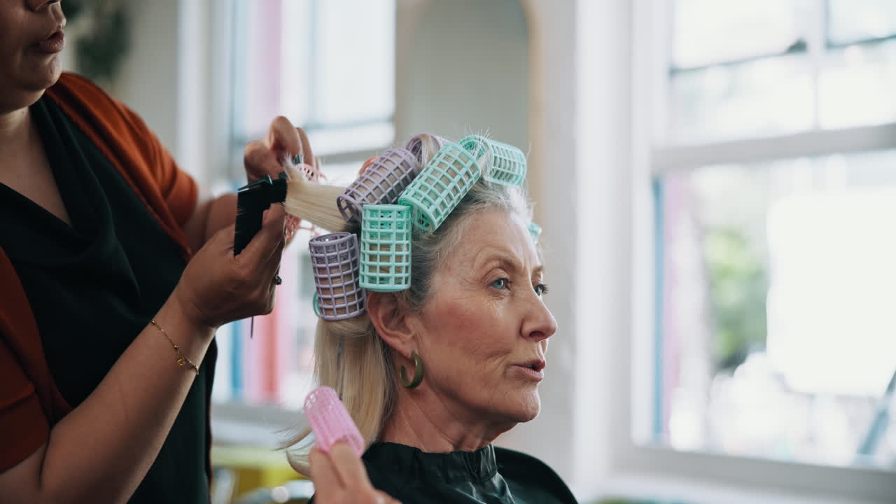 Hairdresser Styling Senior Woman's Hair with Rollers in Salon