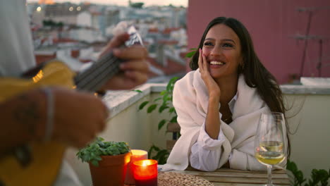 Positive-woman-listening-music-sunset-place-closeup.-Unknown-man-playing-ukulele