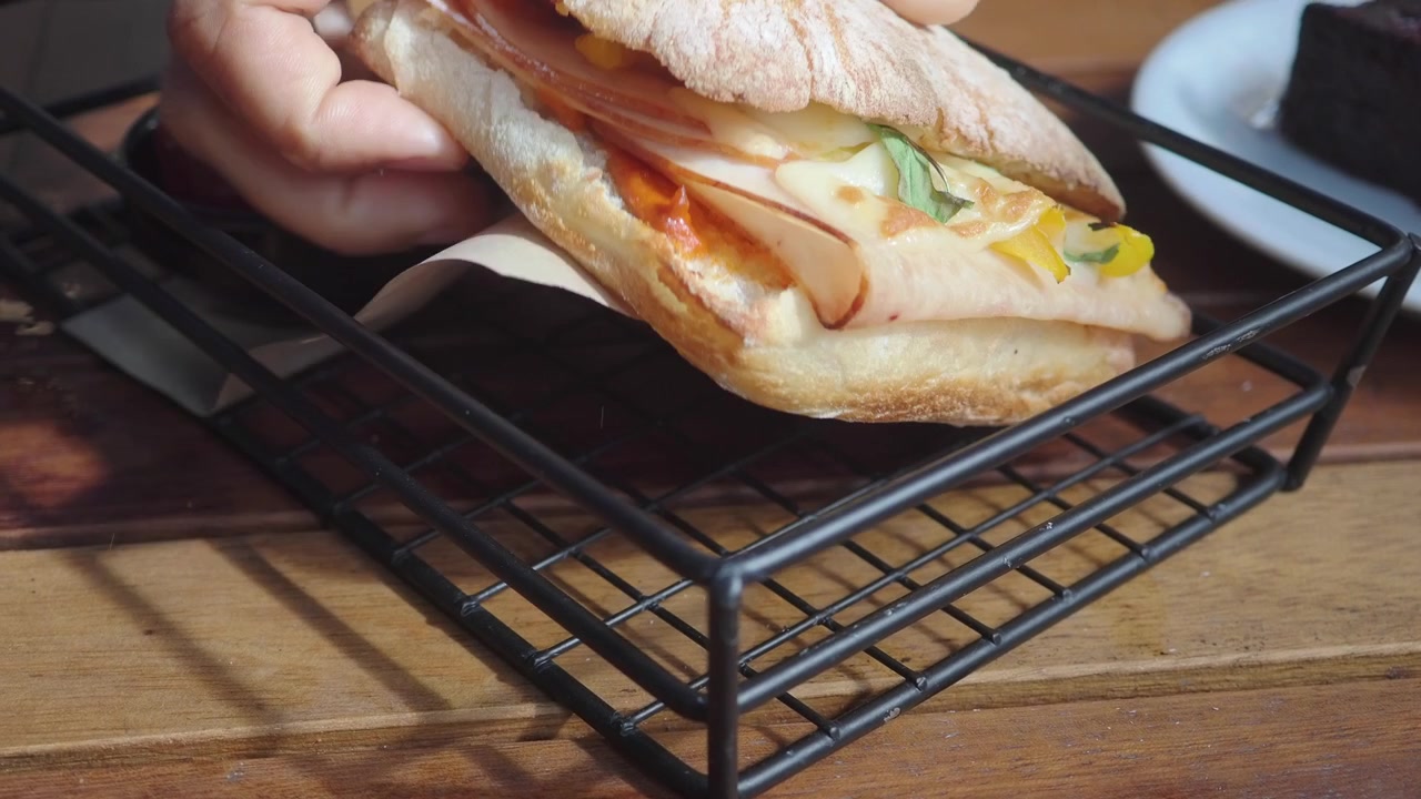 Mano che prende un delizioso sandwich ciabatta con prosciutto e formaggio.