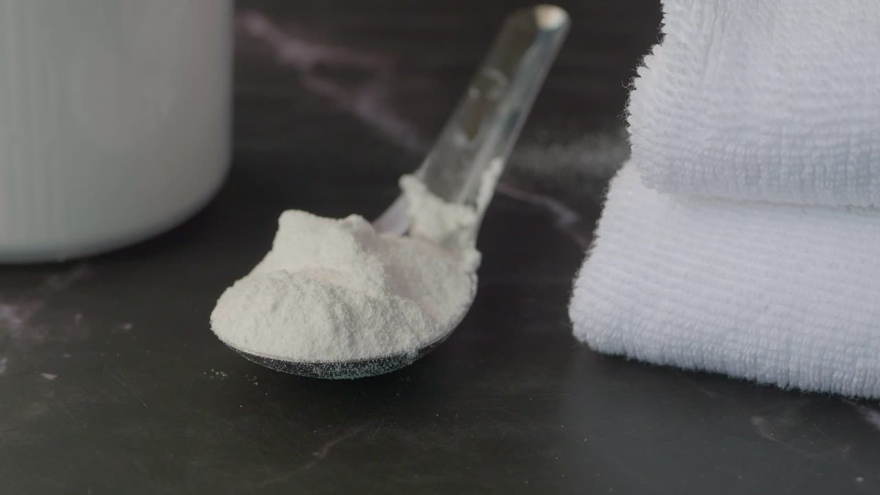 Washing powder in plastic spoon on black background ,