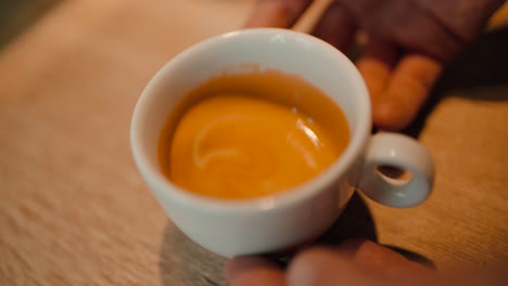 slow motion of pouring milk into a cup of coffee on an old wooden table, top view