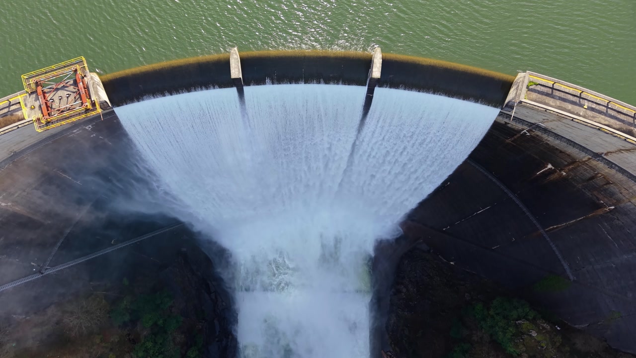 Flying Above Eume River Dam In Galicia, Spain, With Water Release Through Concrete Spillway. aerial topdown shot