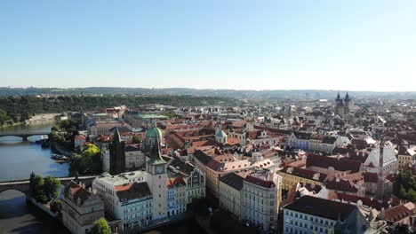aerial pan around the city of praha, czech republic from up above the vltava river with a view of the rooftops of old town, various towers and spires, charles bridge and the prague castle