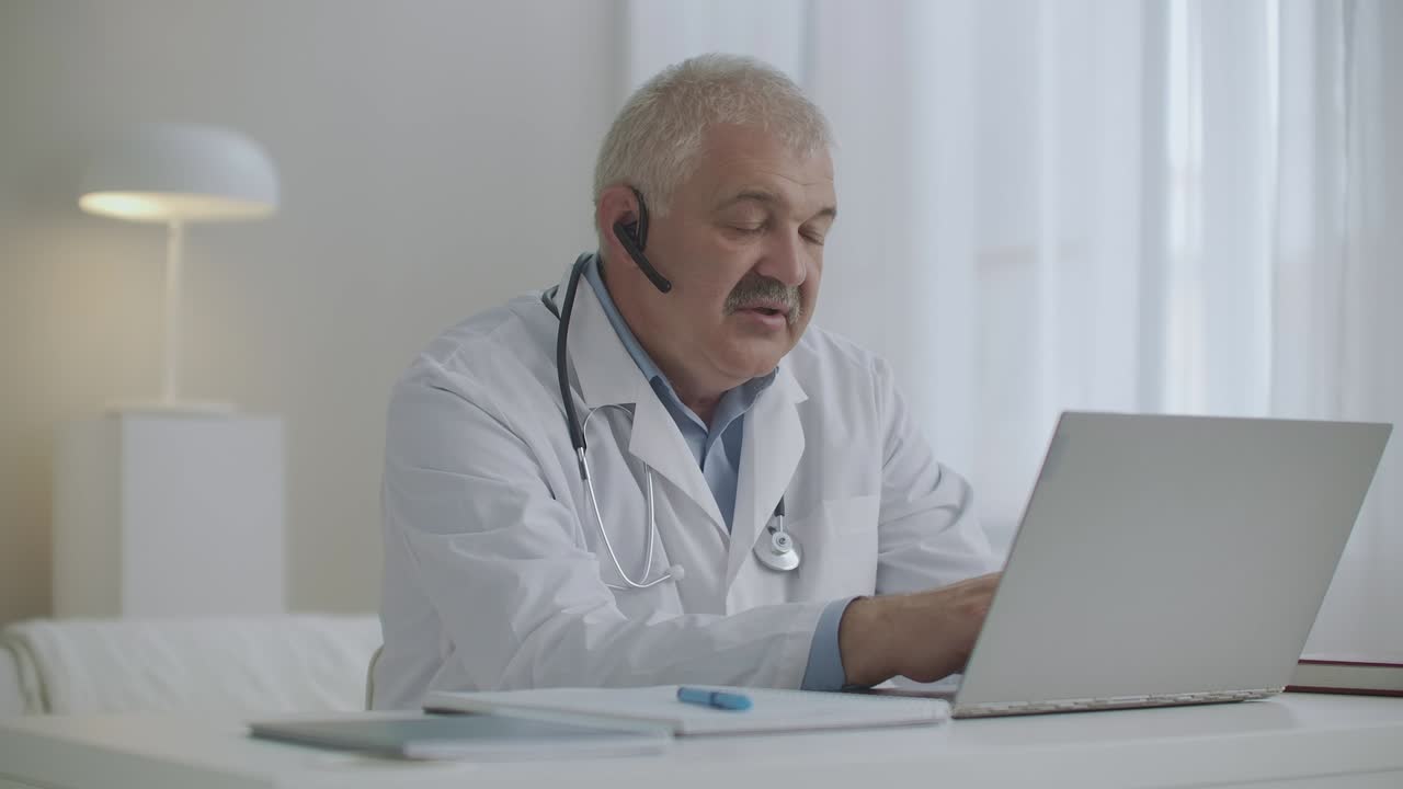 cita en línea con pediatra o terapeuta, médico masculino está trabajando remotamente desde su oficina, usando portátil con videoconferencia