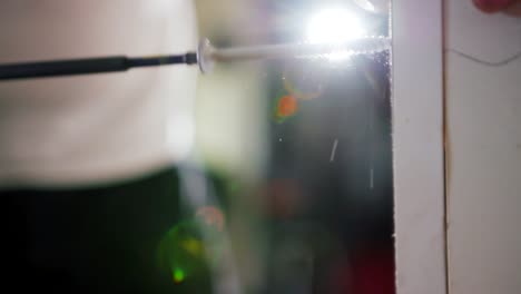 drilling screw into wood with light in background, close shot slow motion