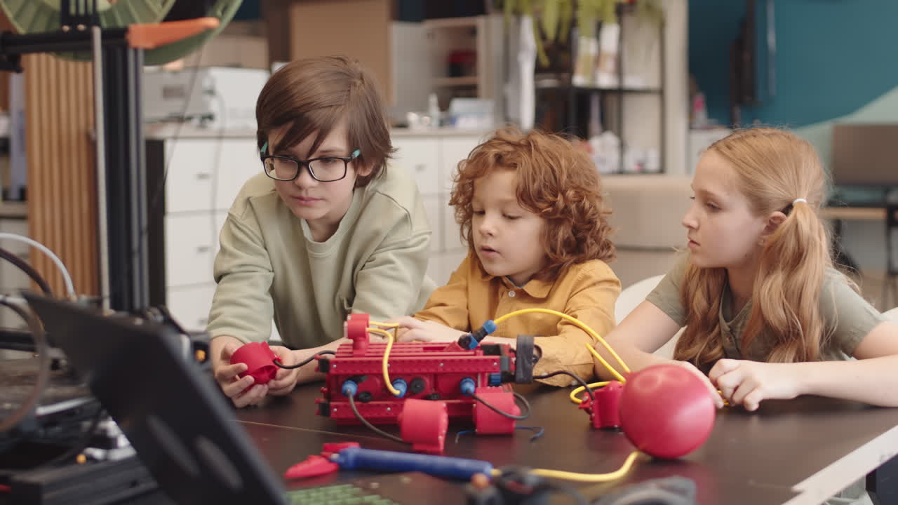 Three Caucasian Pupils Watching Machine Working during Science Lesson
