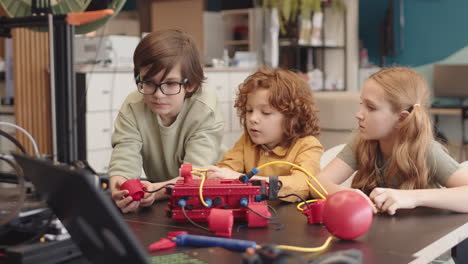 three caucasian pupils watching machine working during science lesson