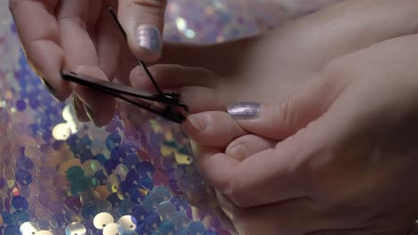 side view in 4k slow motion of woman trimming toenails above sequin fabric