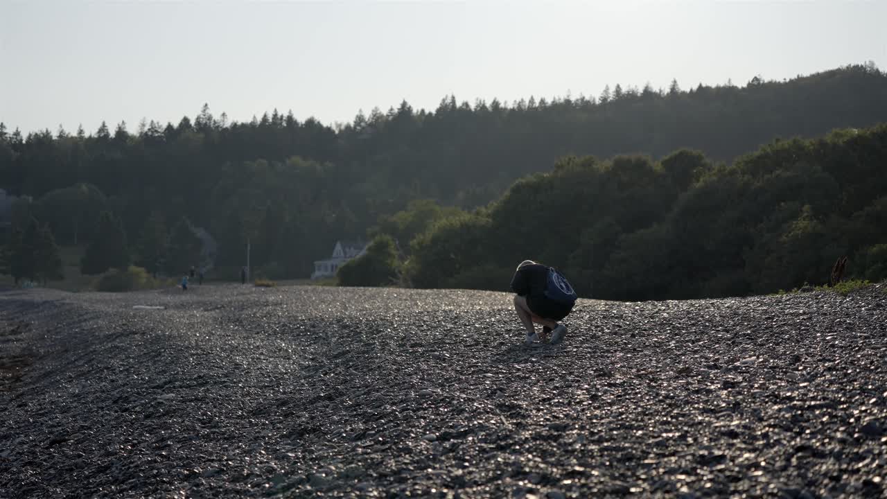 Young girl picking up unique polished stones at Jasper Beach in Maine