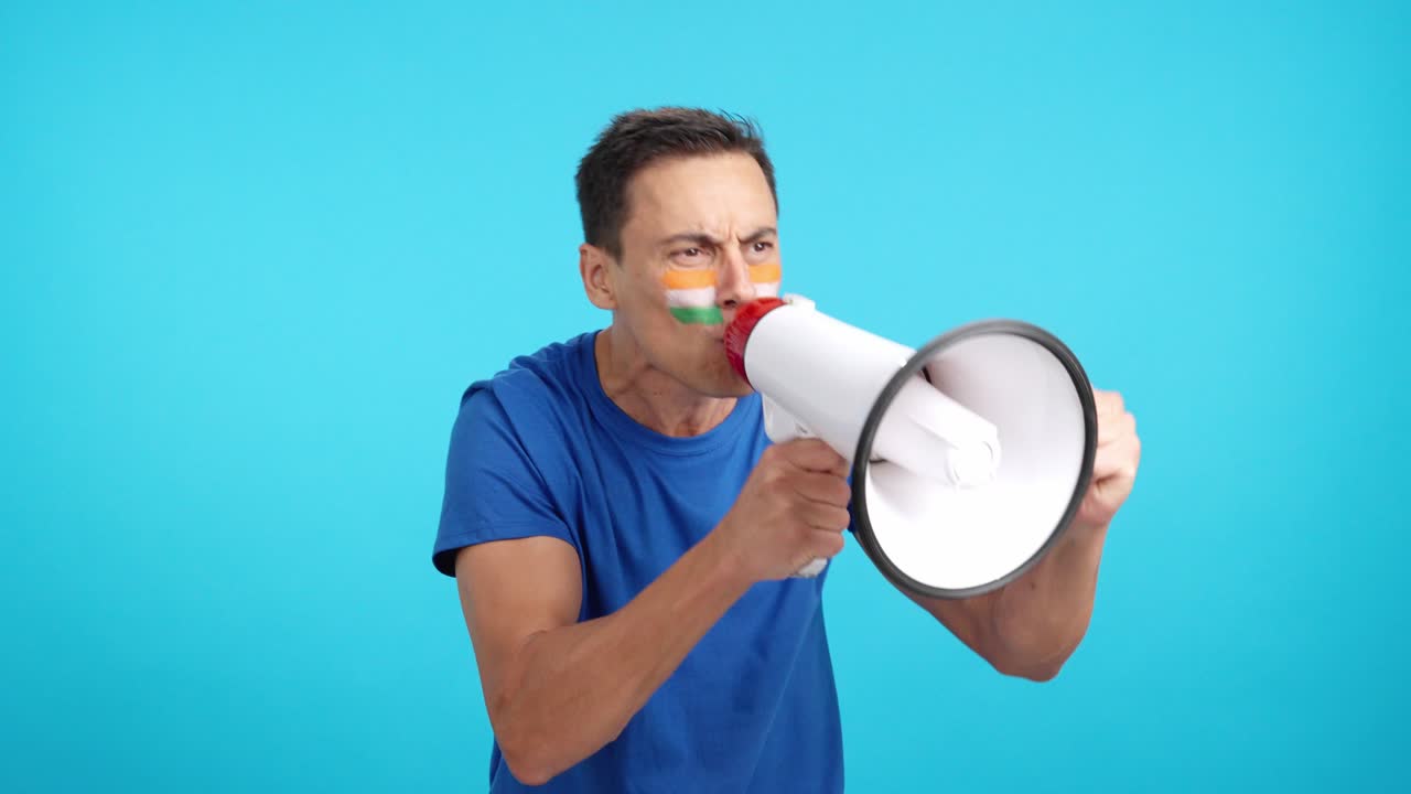 Excited man with indian flag on face using a megaphone