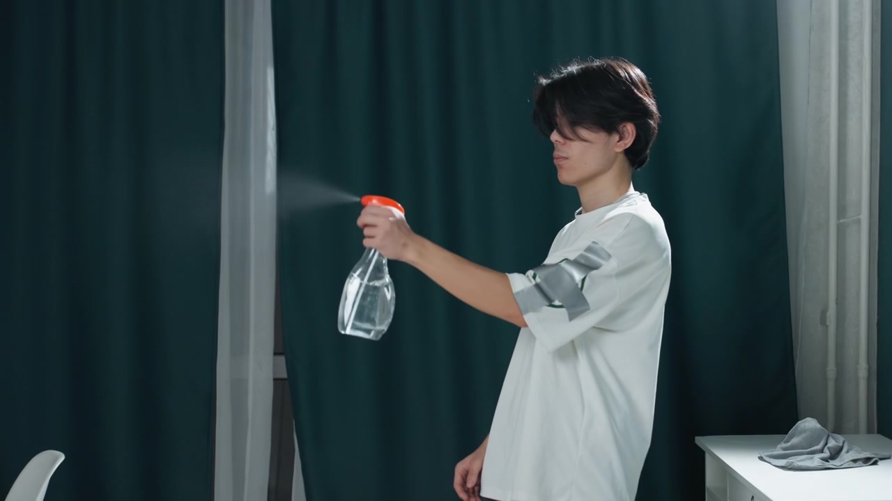Persona energica che dimostra la pulizia. Un individuo asiatico mostra con entusiasmo le tecniche di utilizzo dello spray detergente. Un uomo asiatico entusiasta dimostra metodi di pulizia domestica interagendo con la telecamera.