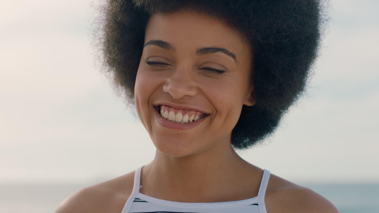 retrato de una mujer hermosa con afro riendo en la playa disfrutando del verano luciendo feliz mujer independiente sintiéndose positiva divirtiéndose en el verano junto al mar imágenes 4k