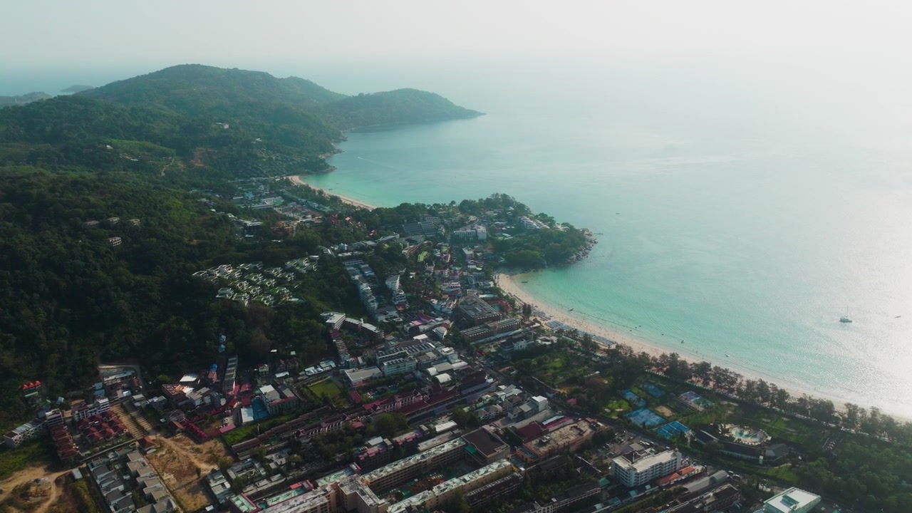 Il drone avanza sopra la città turistica di Phuket, rivelando una baia turchese e il litorale.