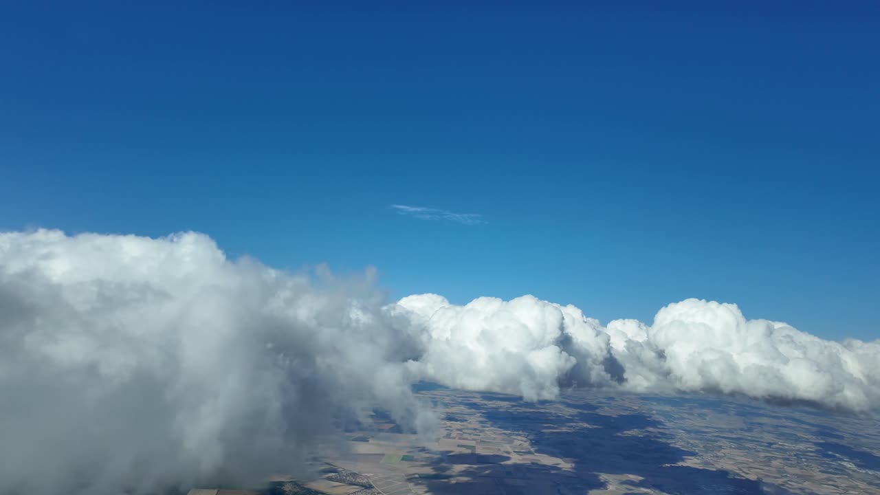 piloto inmersivo pov, como se ve desde la cabina volando en un cielo azul profundo con algunas nubes blancas esponjosas