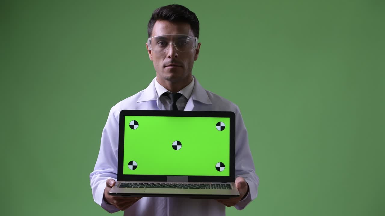 joven hombre hispano guapo médico contra fondo verde