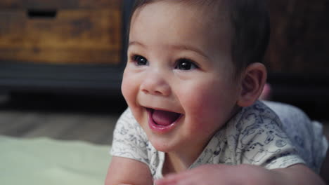 tilting shot from baby hands to his face while he attempts to learn how to crawl