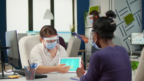 group of multiethnic people with face masks analyzing financial data