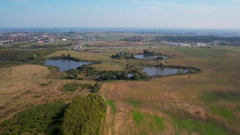 Pequeños-Cuerpos-De-Agua-Ubicados-En-Un-Campo-Enorme-Cerca-De-La-Autopista---Antena-Hacia-Atrás