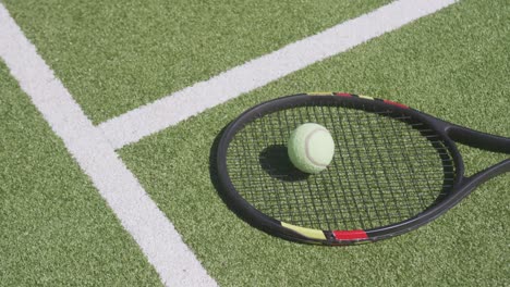 close up of tennis racket and ball on tennis court on sunny day