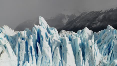 the spiked tops of a glacier stand against rugged mountains 4