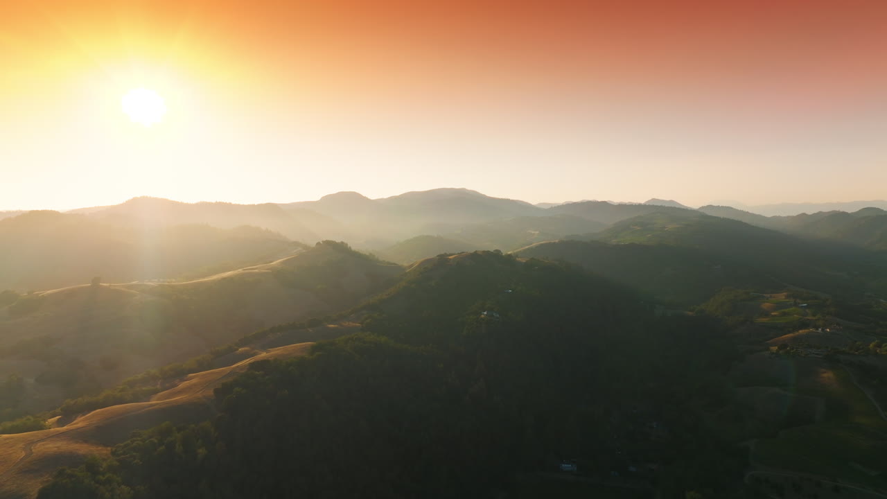 Green vineyards overgrowing the beautiful hills of California, USA. Mountainous panorama in the rays of sunset. Pink skies at backdrop.