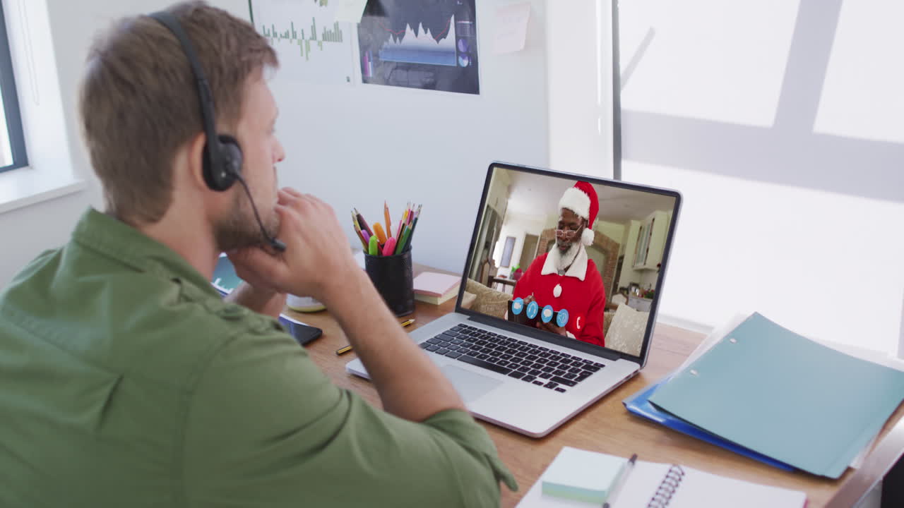 Kaukasisk mand med telefonheadset på videochat via bærbar computer derhjemme i julen.