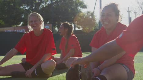 Equipo-De-Fútbol-Femenino-Calentando-Con-Estiramientos-En-El-Entrenamiento-Contra-El-Sol-Abrasador