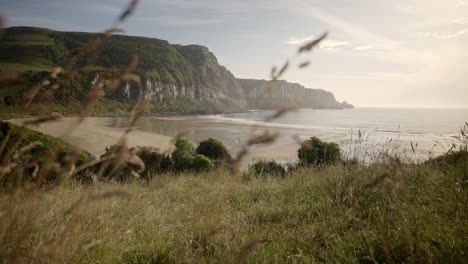 Fantastischer-Strand-Bei-Sonnenuntergang-Mit-Wunderschönem-Licht,-Das-Vor-Einer-Wiese-Auf-Einem-Hügel-Durchscheint