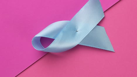 blue silk ribbon wrapped in a loop on a pink background, prostate cancer awareness symbol