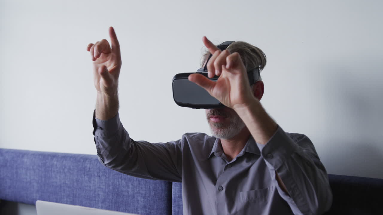 hombre de negocios caucásico sentado en el sofá usando vr googles en la oficina