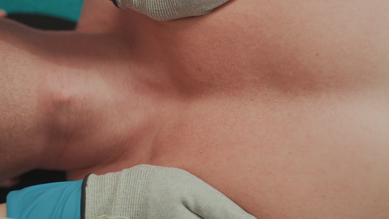 terapia de microcorrente no peito de homem branco, terapeuta com luvas aplicando eletrodo no tronco, contato próximo com a pele, interface de gel, ambiente de spa clínico, foco em fisioterapia para recuperação muscular