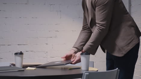 businessman sitting and opening laptop computer while drinking takeaway coffee in boardroom 1