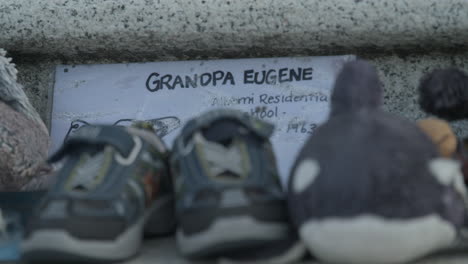 Close-up-of-the-BC-Legislative-Assembly-buildings-with-a-memorial-for-Indigenous-Children-victims-on-the-front-steps-in-Victoria-BC,-showing-children's-shoes-and-a-note