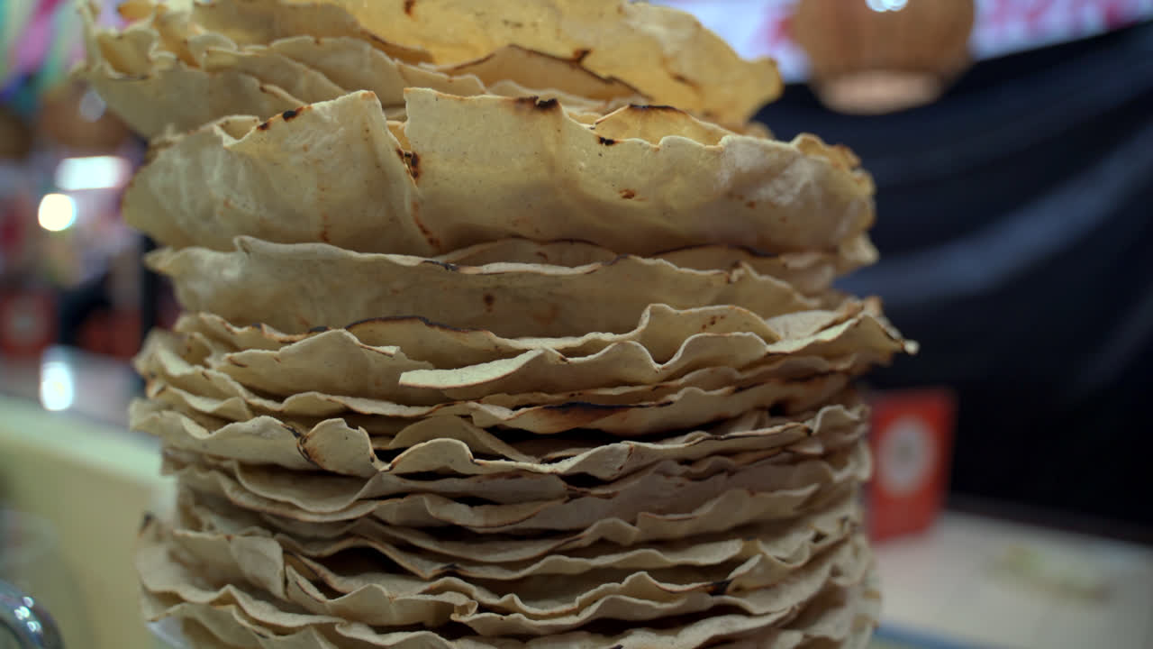 Tlayudas stacked on market counter showing crisp texture and traditional Oaxacan street food, detailed closeup