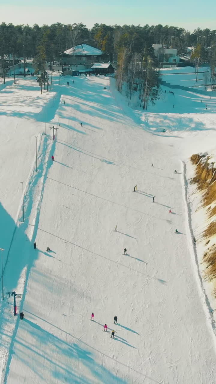 aerial panorama of comfortable track at ski resort on snowy hill slope with evergreen wood on sunny day