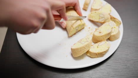 in a home kitchen a woman cuts cantucci biscuits before second baking in oven