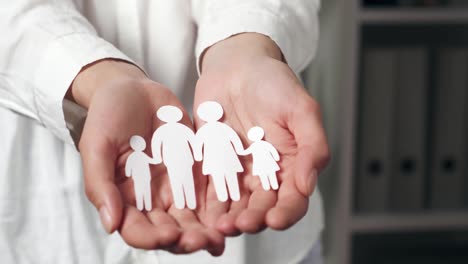 manos femeninas de primer plano sosteniendo una familia ilustrada en silueta de papel. silueta familiar de personas
