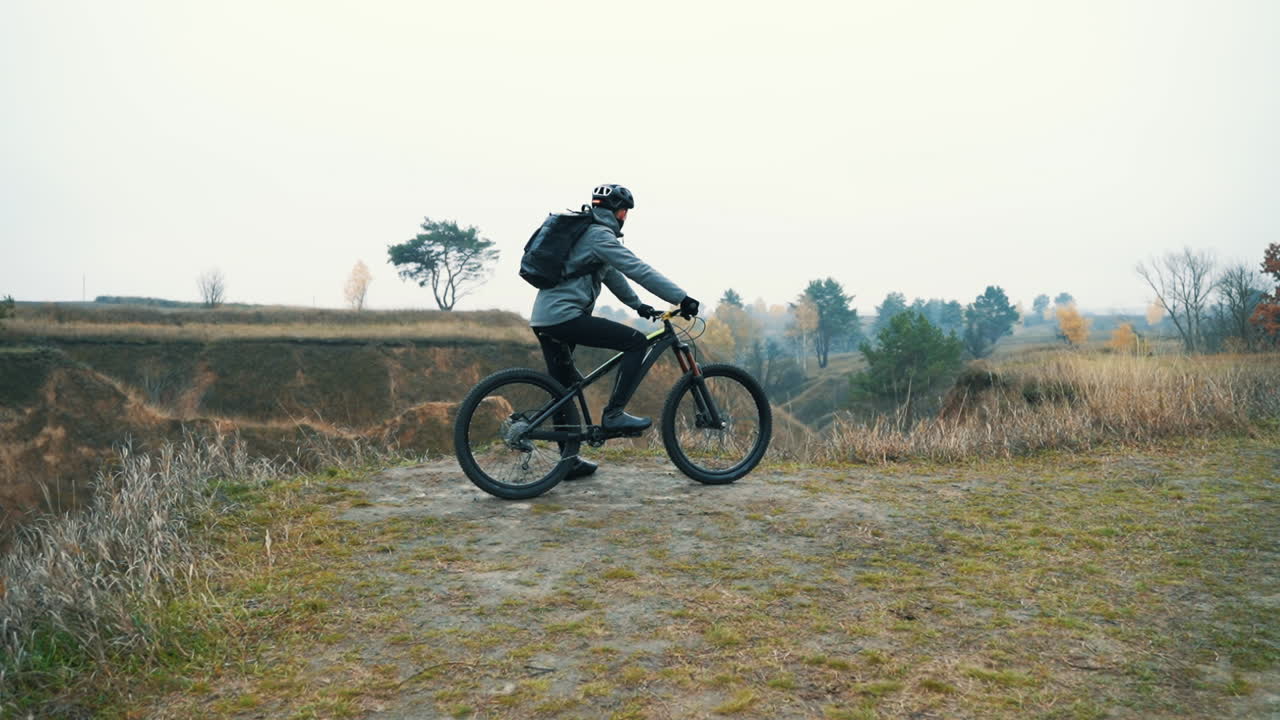atleta ciclista masculino listo para andar en bicicleta de montaña en la colina por la carretera en medio del valle