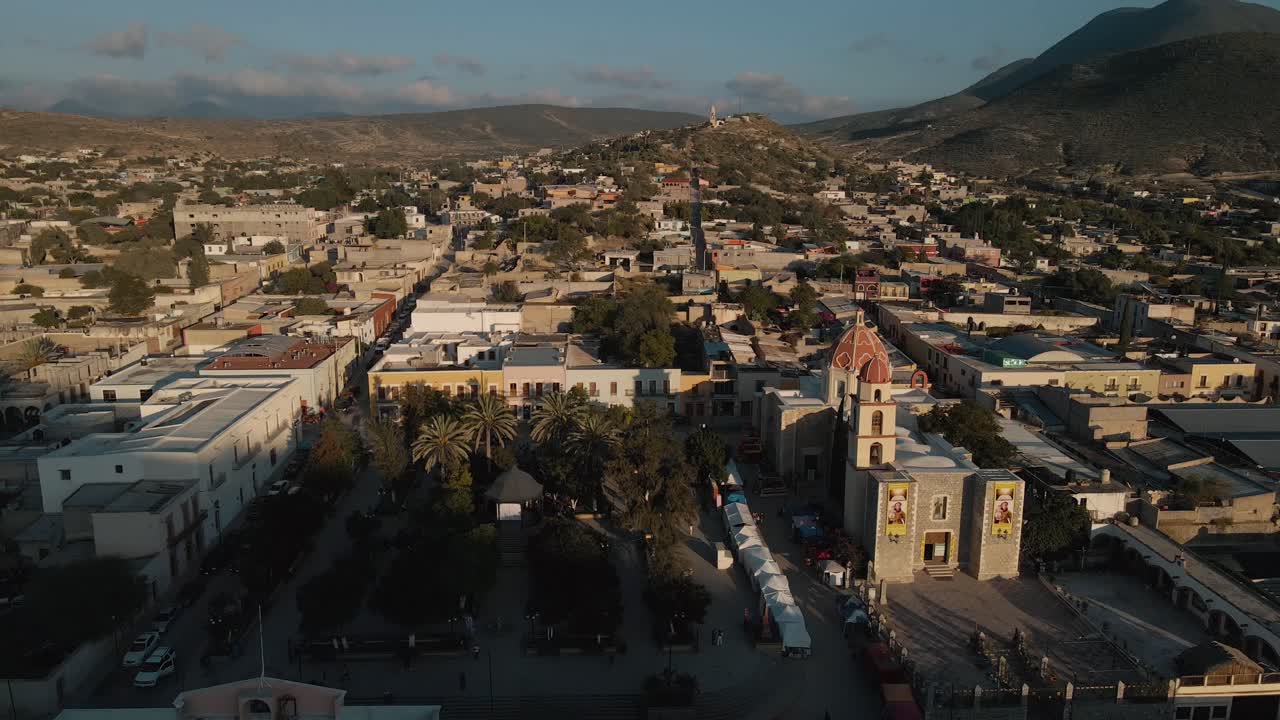 vista panorámica aérea sobre un centro de la ciudad mexicana con una iglesia y una plaza con palmeras
