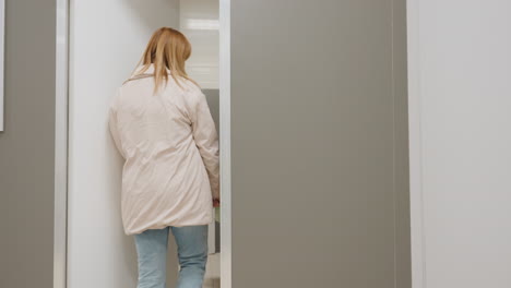 Back view of female manager walking through corridor towards door, opening it smoothly and closing it behind her, portraying professional routine, and daily business environment
