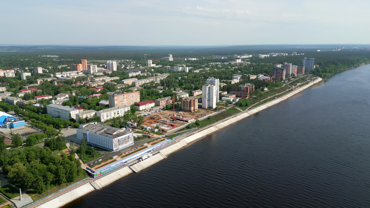 Aerial view of a city along a river with an embankment and residential buildings