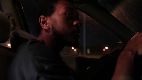 joven negro afroamericano conduce un coche por la noche de cerca