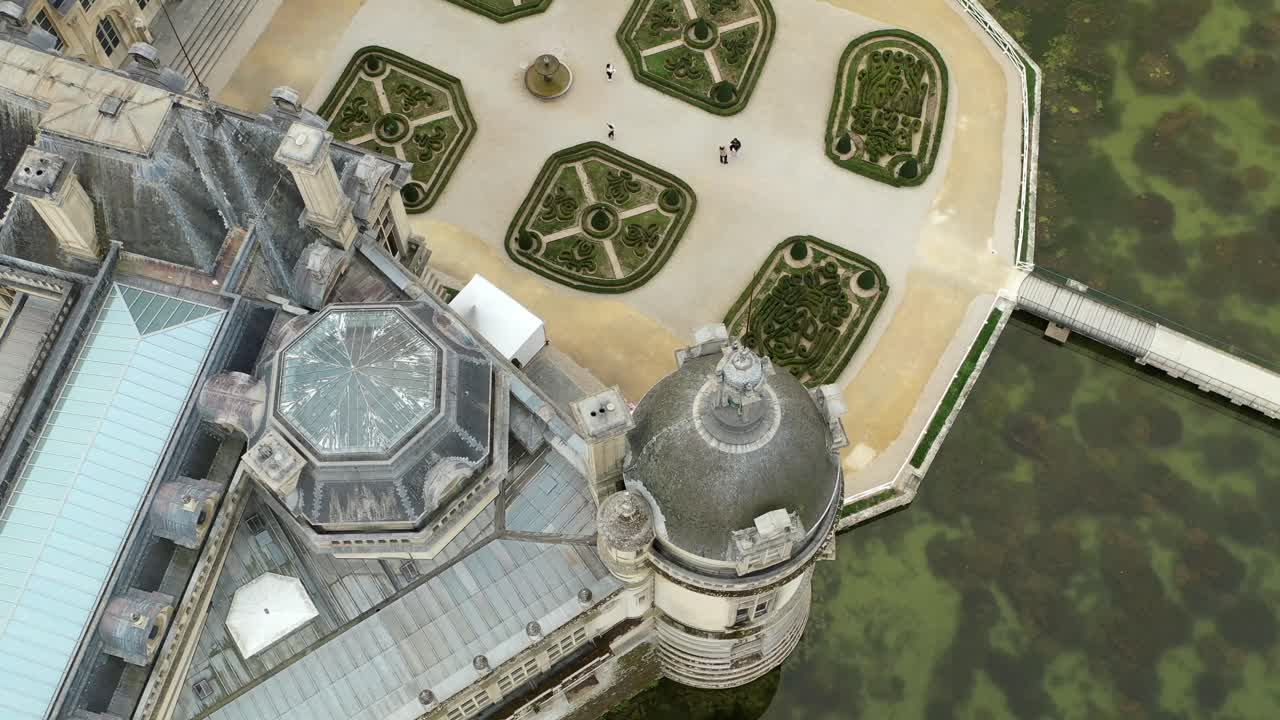 Aerial top down close up of Chateau de Chantilly ornate tower and gardens, France. Historic French castle details, architectural heritage