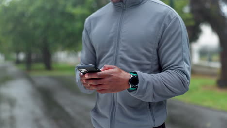 hombre enviando mensajes de texto en su teléfono inteligente bajo la lluvia